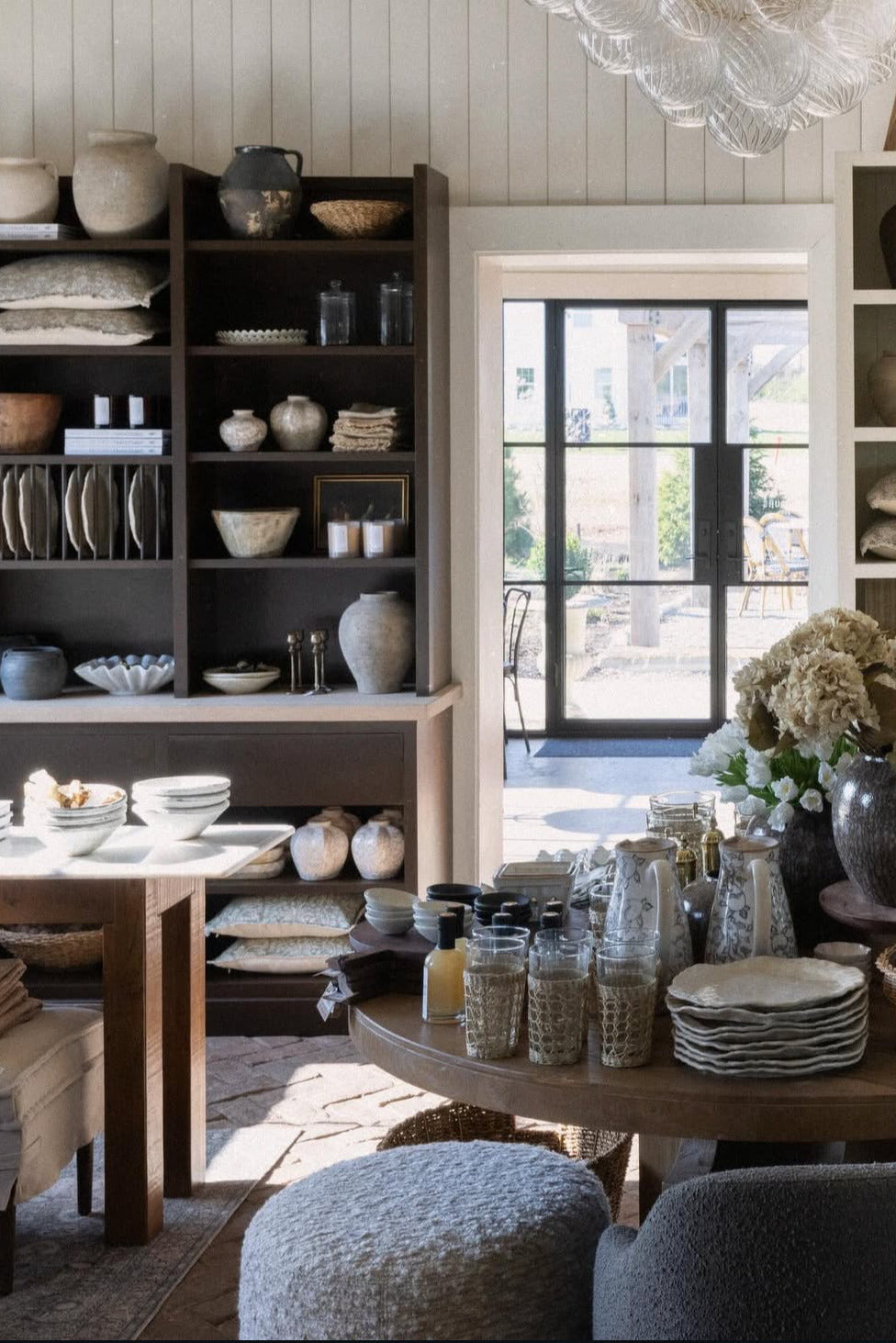 Dining room with wooden table, chairs, and shelves filled with decorative items.